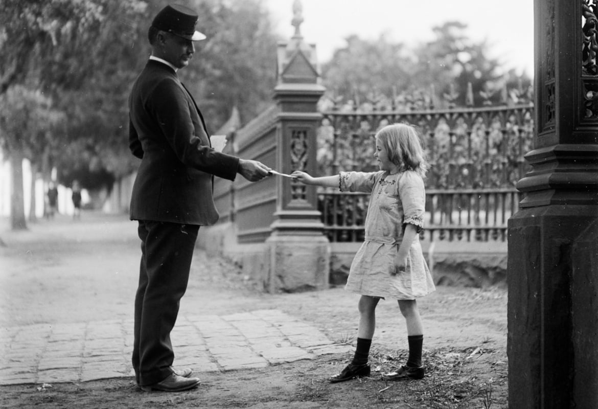 A man in uniform hands a letter to a young girl