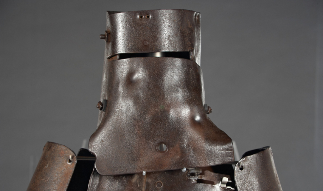 Close-up image of Ned Kelly's suit of armour from the shoulders up. The armour sits against a grey background.