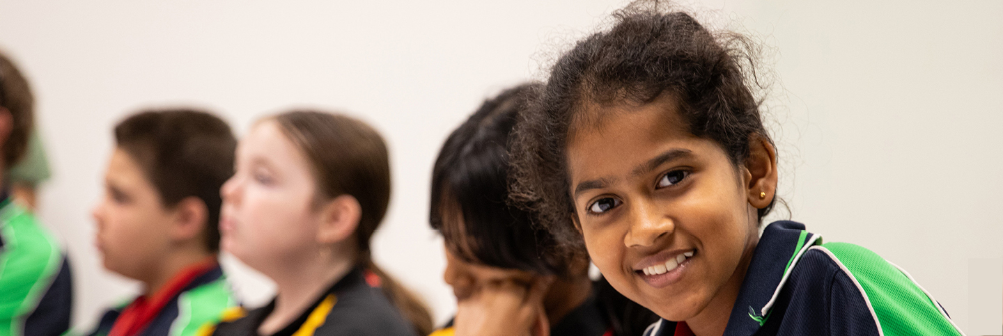 Group of students in a writing workshop. The student on the far right is looking directly at the camera and smiling.