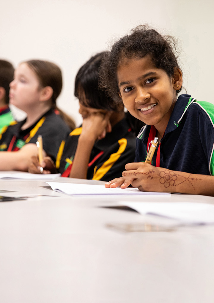 Group of students in a writing workshop. The student on the far right is looking directly at the camera and smiling.
