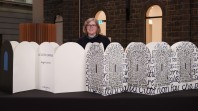 A woman standing behind a large white and black fold out book