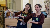 two young women smiling and welcoming visitors to the library