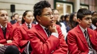 Colour photo of an audience of schoolchildren wearing red blazers