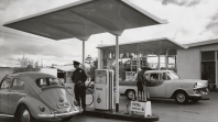 Black and white photo of two men filling the petrol of two cars