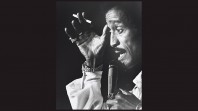 black and white portrait of Sammy Davis Jnr with microphone and cigarette