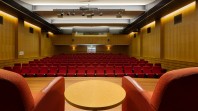 Conference Room from the stage with armchairs and rows of red seats