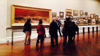 A man talks to a group of visitors in an art gallery