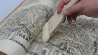 Colour photo of Library conservation team using a soft brush on an antique book