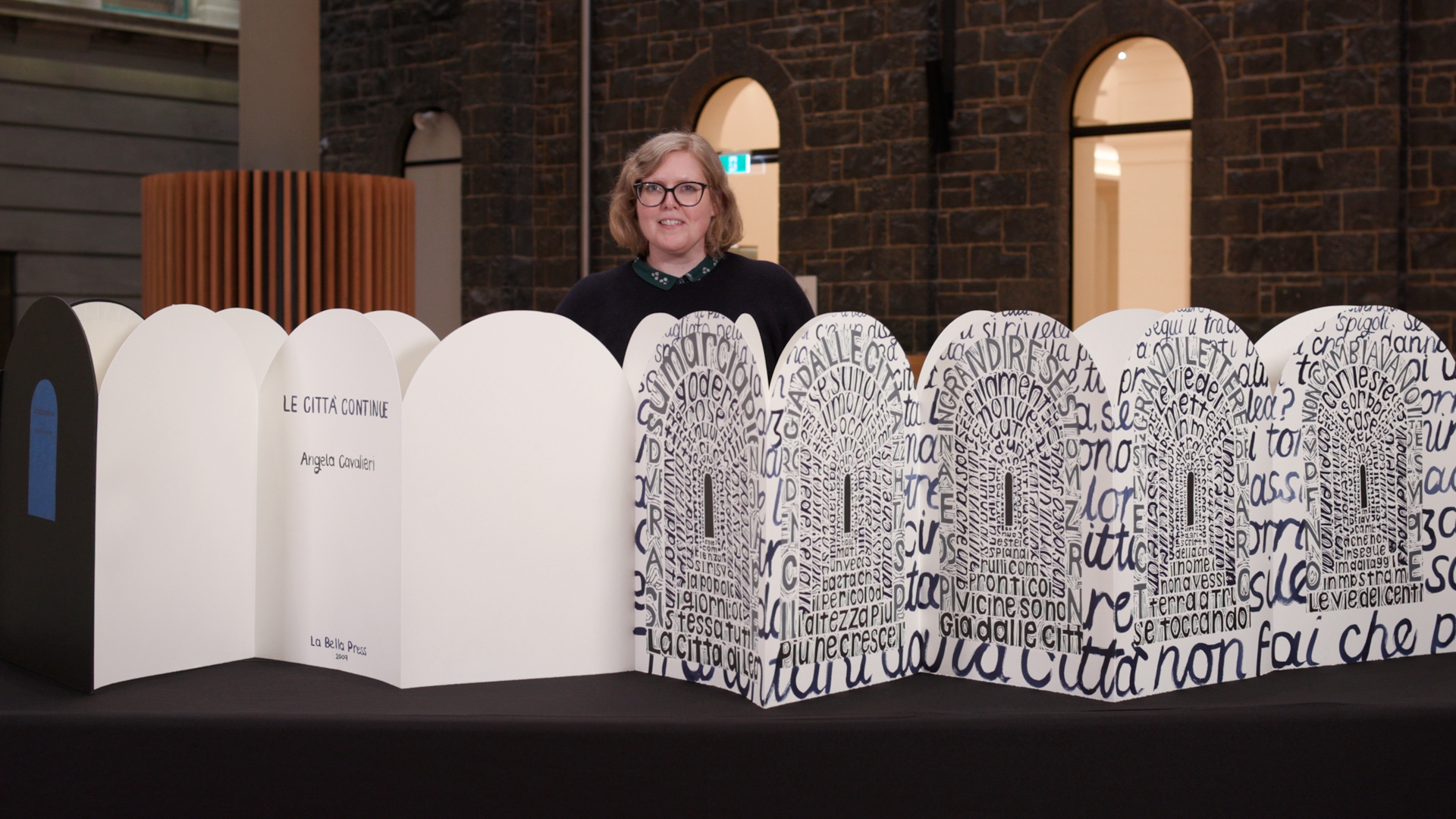 A woman standing behind a large white and black fold out book