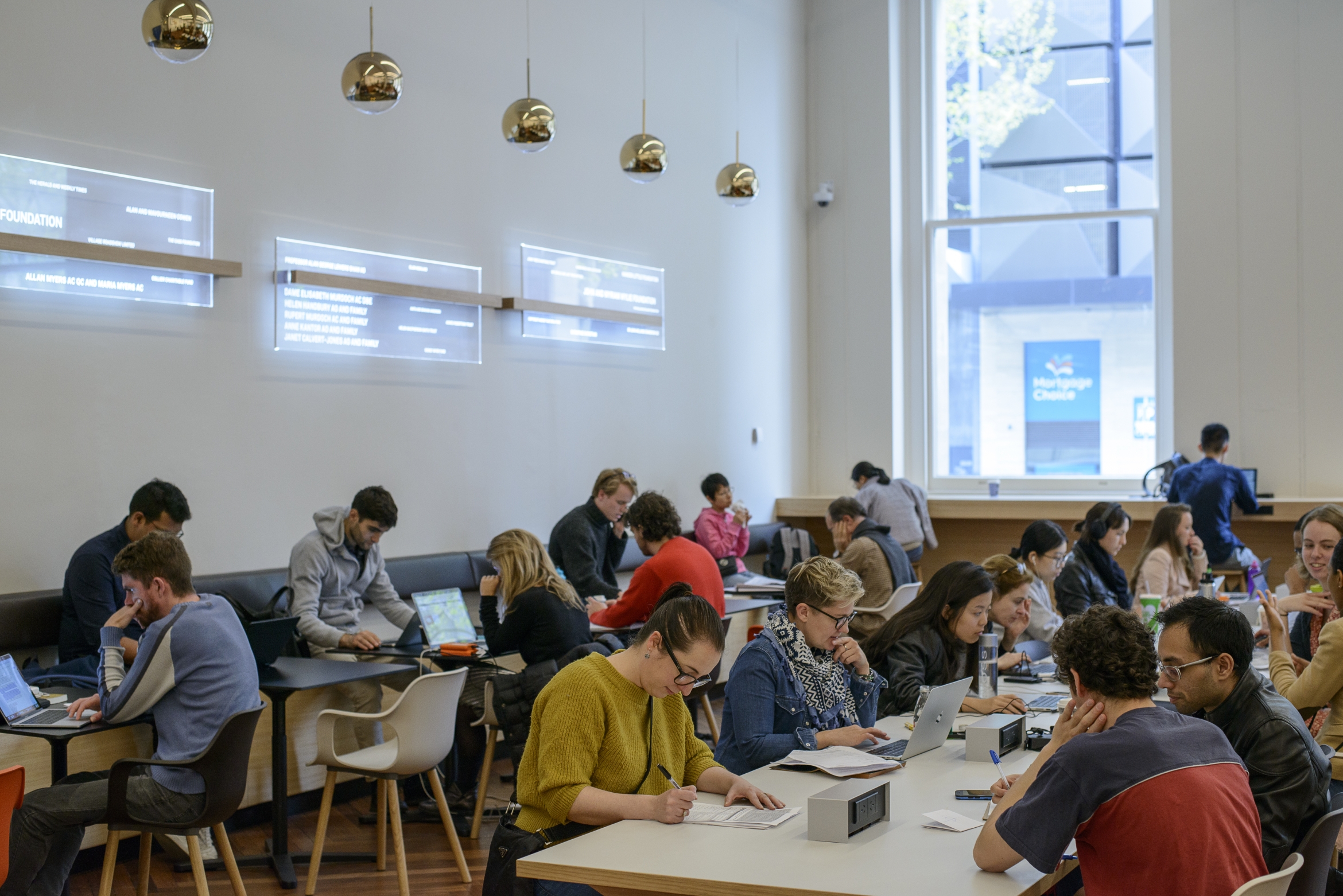 people studying at long tables in a bright room