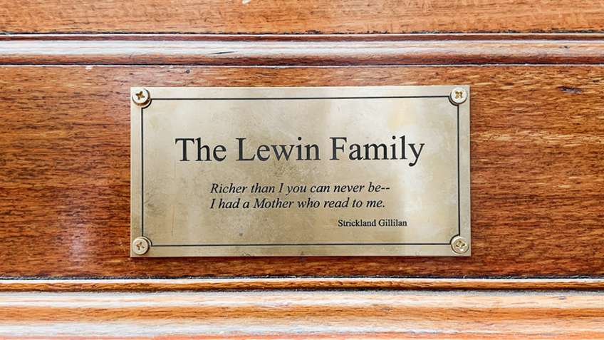 An inscribed bronze plaque on a wooden background