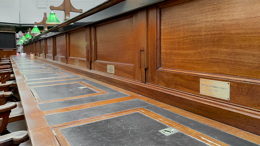 A row of desks with bronze plaques inscribed into them
