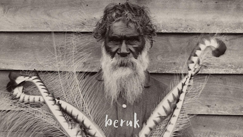 Photo of Indigenous man with long beard, holding feathers.