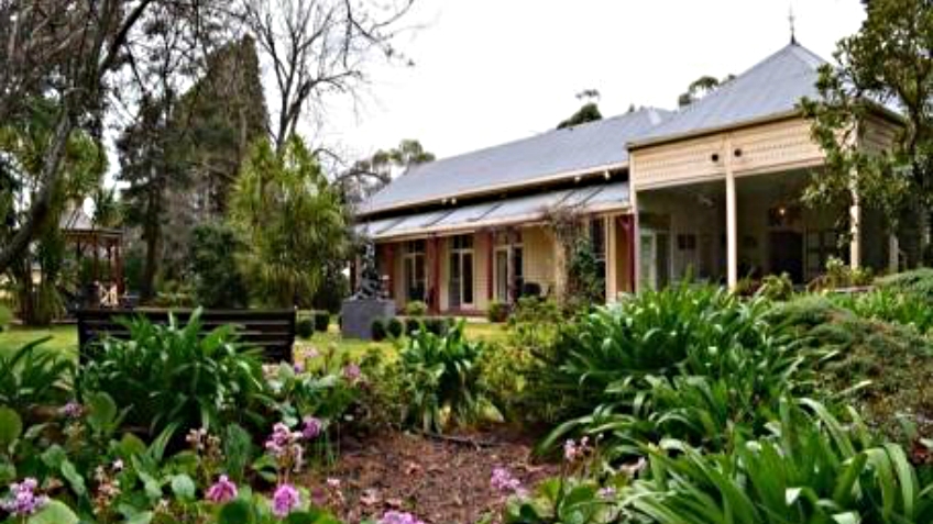 Colour photo of Federation-era Dromkeen homestead, with verandah and agapanthus