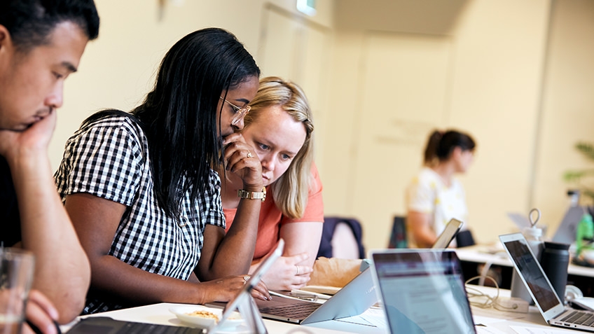 Two women and a man working on laptops at a table