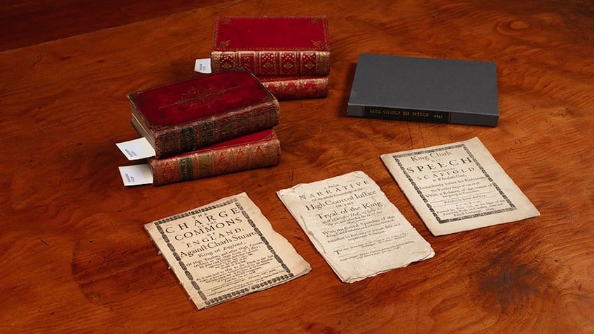 Image of rare books and pamphlets from the John Emmerson Collection at State Library Victoria placed on a brown table. There are five books and three pamphlets. 