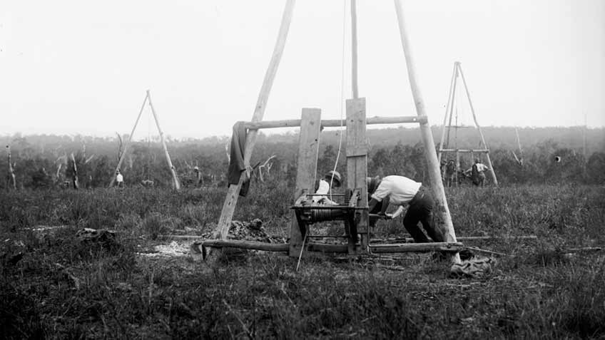 1920-1925 glass negative image. Early bore holes, testing coal. Shows men operation mining windlasses