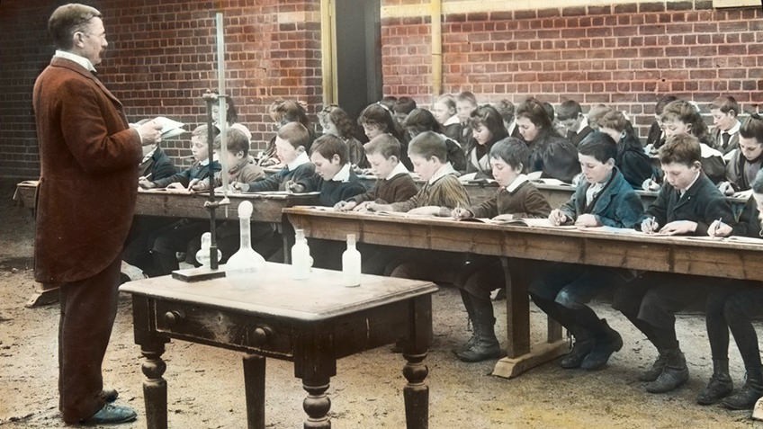tinted ca 1900 photo of teacher standing before an outdoor classroom of children