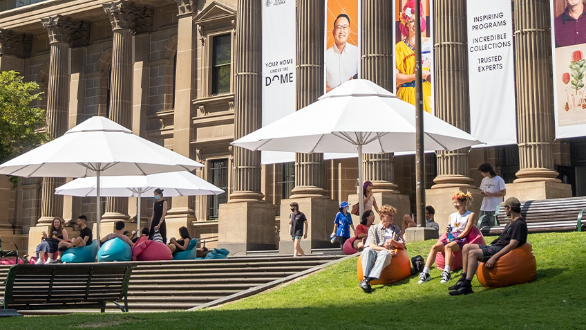 Library forecourt with umbrellas and people talking and reading books