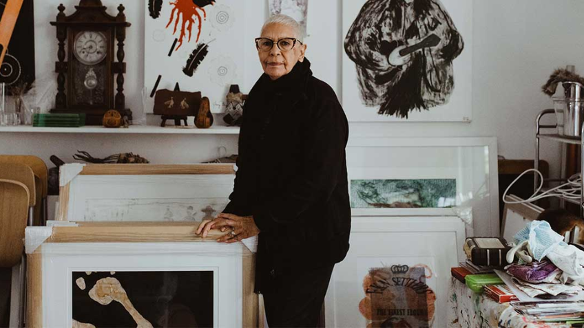 Portrait of artist Glennys Briggs in studio, surrounded by artwork.