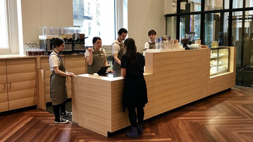 parquet floored foyer with bright windows, coffee bar with baristas and customers