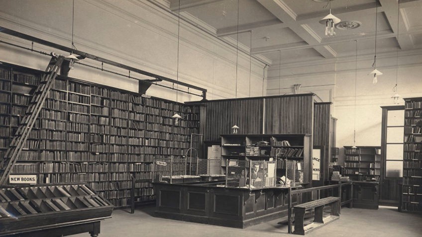 sepia photo of library room with ornate ceiling and shelves of books