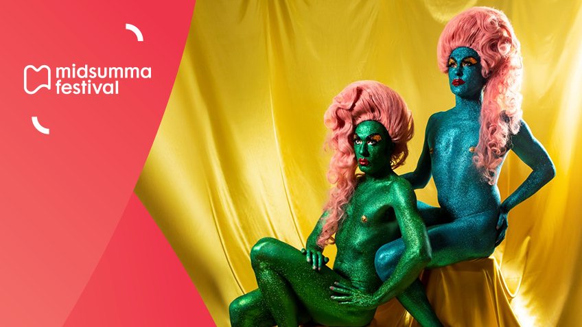 Artists, The Huxleys dressed in green and blue glitter body paint and both wearing fairy-floss pink wigs posing in front of a gold sheet.