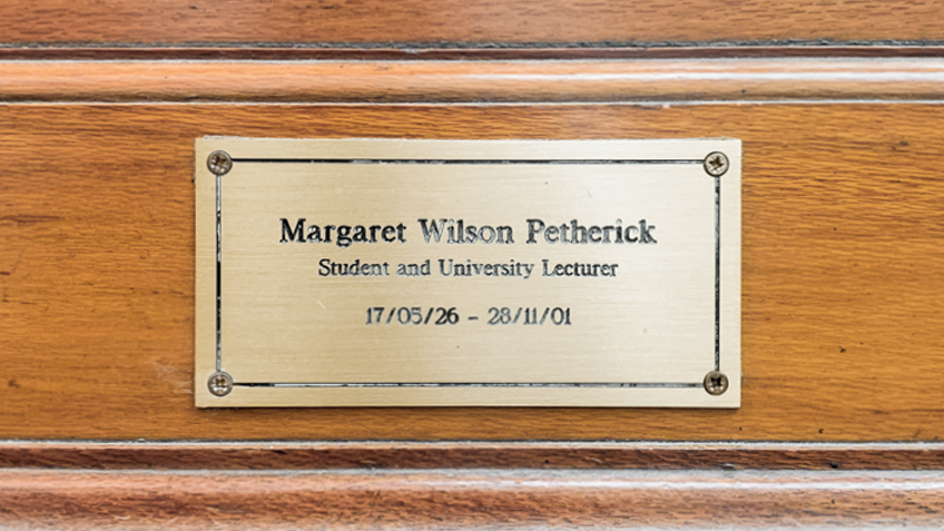 A bronze plaque inscribed to Margaret Petherick on a wooden background