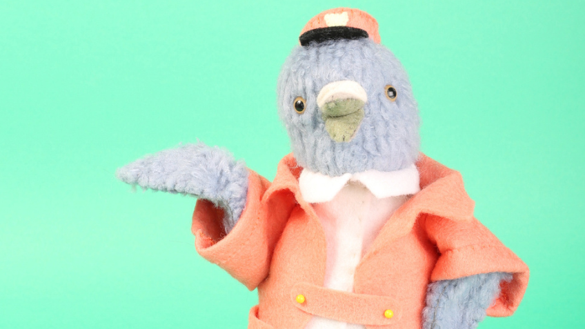 A furry bird in a conductor uniform hand-crafted by Soft Stories.