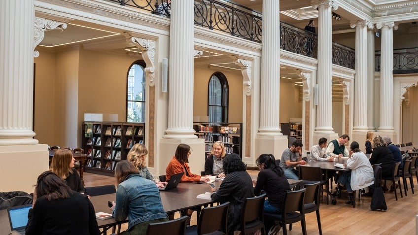 people at tables in grand space with columns