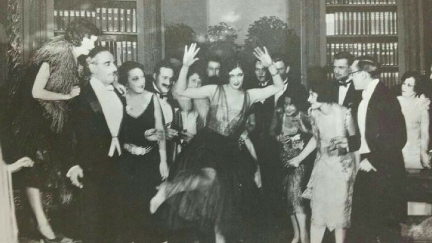 Black and white photograph of a high society party featuring a lady centre dancing