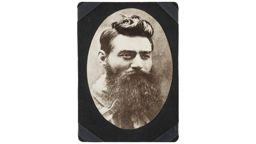 Black and white headshot photograph of Ned Kelly, a man with dark hair and long beard.