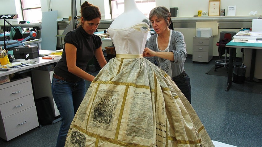 Photo of two women putting the Press Dress on a mannequin