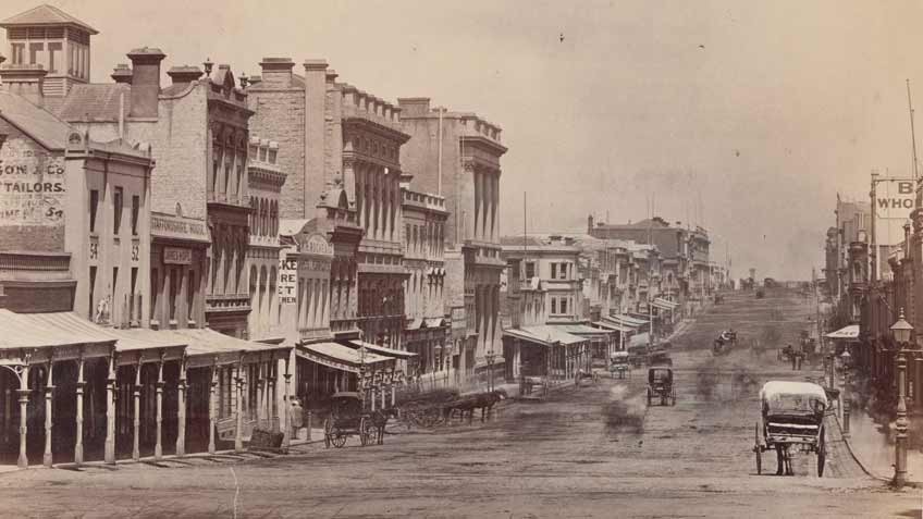 Photograph of Collins Street from Swanston Street, Melbourne, ca. 1872. Shows buildings including Staffordshire House and W. H. Rocke & Co. Several horse and carriages can be seen along the street. 