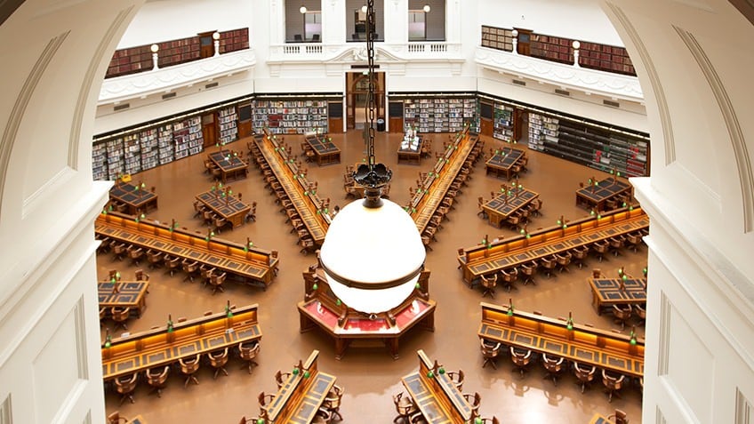 Photo of desks in the La Trobe reading room through an archway with a light globe in the centre