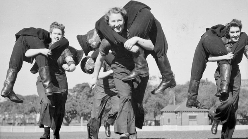 black and white photo of three uniformed women on an oval carrying male dummies 