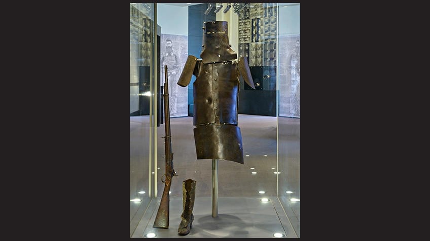 glass display case with Ned Kelly helmet, armour, rifle and boot