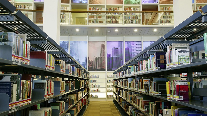 colour photo of library interior with books of shelves and glassed-in mezzanine