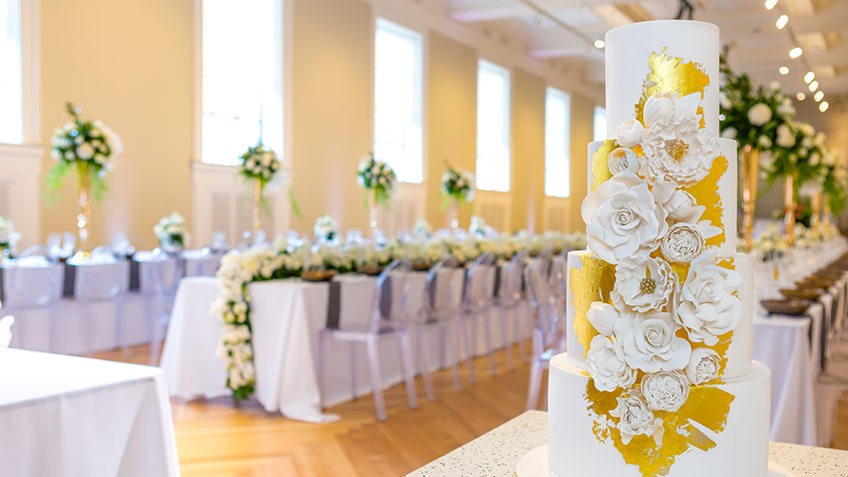 elegant wedding venue with formal tables, cake and sunlit windows