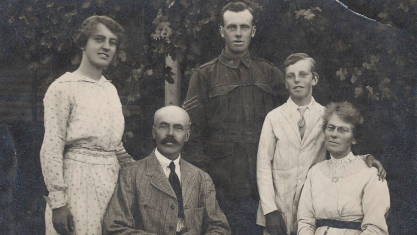 Group outdoor portrait of five people, man and woman seated, woman standing on left, man in WWI uniform standing in centre, boy standing on right 