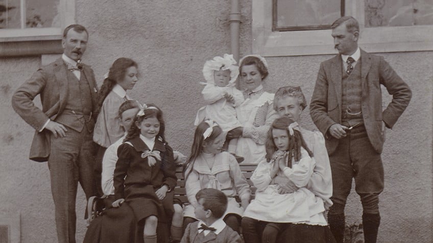 Black and white photograph of a family in front of house, c 1900