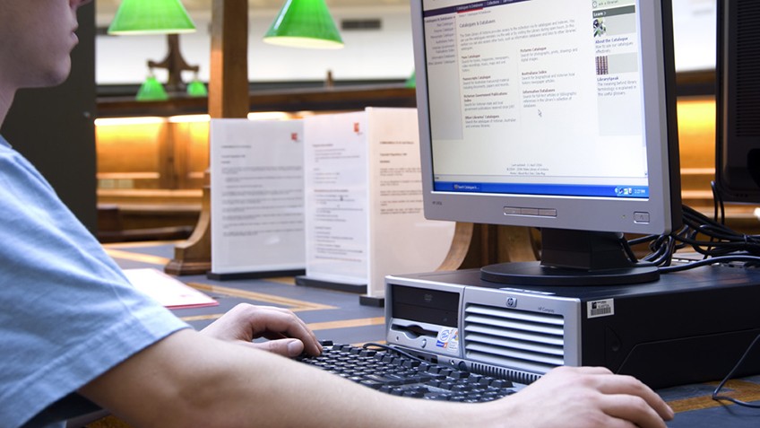 Colour photo of a person using a computer in the La Trobe Reading Room, State Library Victoria