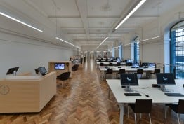 desks and tables in parquet-floored white gallery
