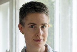 woman with short grey hair photographed backlit against white curtains