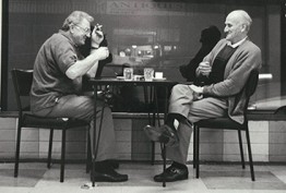 CFOV 2021 coffee A black and white image of two men sitting outside a coffee shop sipping drinks and smoking