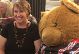 Smiling woman seated next to a giant teddy
