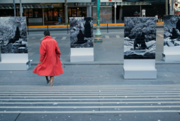 Grey city scene with a person walking in a red coat