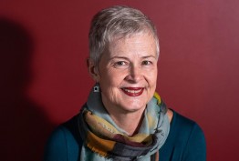 2018 Redmond Barry Fellow Jillian Graham portrait of older woman wearing a scarf and teal jumper against red background