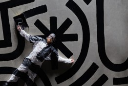 Behind the paint tile Man lying on black and white pattered ground