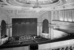 black and white interior shot of theatre stage, chandeliers and seating